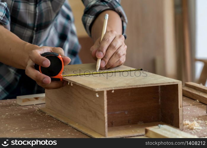 Carpenter working on wood craft at workshop to produce construction material or wooden furniture. The young Asian carpenter use professional tools for crafting. DIY maker and carpentry work concept.