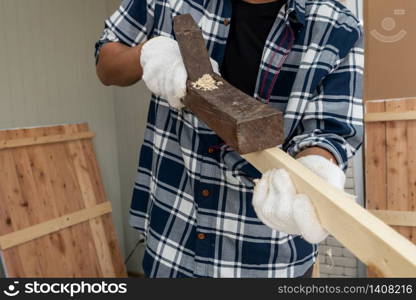 Carpenter working on wood craft at workshop to produce construction material or wooden furniture. The young Asian carpenter use professional tools for crafting. DIY maker and carpentry work concept.