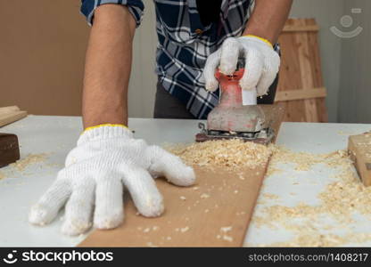 Carpenter working on wood craft at workshop to produce construction material or wooden furniture. The young Asian carpenter use professional tools for crafting. DIY maker and carpentry work concept.