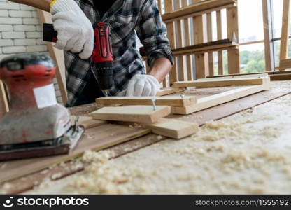 Carpenter working on wood craft at workshop to produce construction material or wooden furniture. The young Asian carpenter use professional tools for crafting. DIY maker and carpentry work concept.