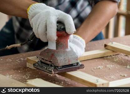 Carpenter working on wood craft at workshop to produce construction material or wooden furniture. The young Asian carpenter use professional tools for crafting. DIY maker and carpentry work concept.