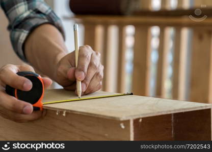 Carpenter working on wood craft at workshop to produce construction material or wooden furniture. The young Asian carpenter use professional tools for crafting. DIY maker and carpentry work concept.