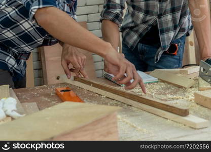 Carpenter working on wood craft at workshop to produce construction material or wooden furniture. The young Asian carpenter use professional tools for crafting. DIY maker and carpentry work concept.