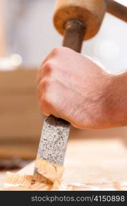 Carpenter working with a chisel in his workshop; close-up on chisel