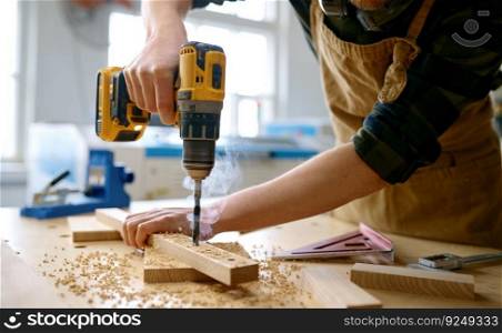 Carpenter working with drill leaning over table at carpentry workshop. Repairman assembling wooden parts using professional instrument. Closeup view. Carpenter working with drill leaning over table at carpentry workshop