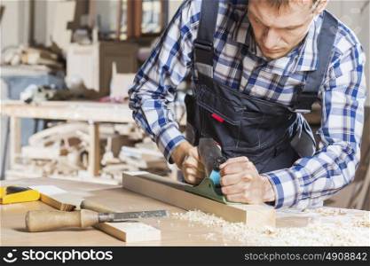 Carpenter working with plane in his studio. Carpenter at work