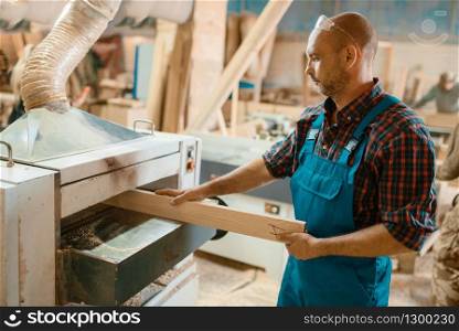 Carpenter works on plane machine, woodworking, lumber industry, carpentry. Wood processing on furniture factory, production of products of natural materials