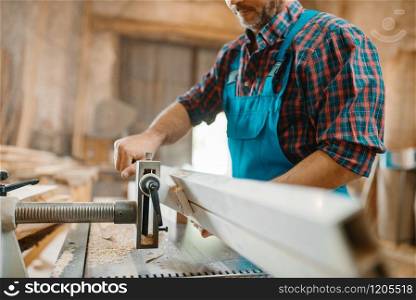 Carpenter works on plane machine, woodworking, lumber industry, carpentry. Wood processing on furniture factory. Carpenter works on plane machine, woodworking