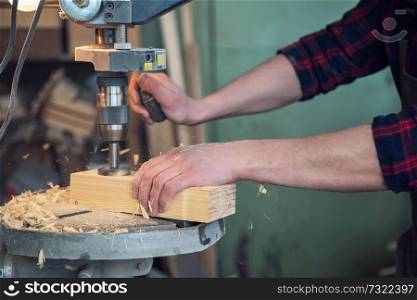 Carpenters with electric drill machine drilling wooden board at workshop. Profession, carpentry and woodwork concept.. Carpenters with electric drill machine drilling wooden board