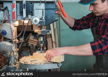 Carpenters with electric drill machine drilling wooden board at workshop. Profession, carpentry and woodwork concept.. Carpenters with electric drill machine drilling wooden board