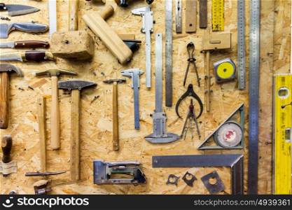 carpentry, woodwork and equipment concept - work tools hanging on wall at workshop. work tools hanging on wall at workshop