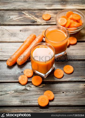 Carrot juice in a glass. On wooden background. Carrot juice in a glass.