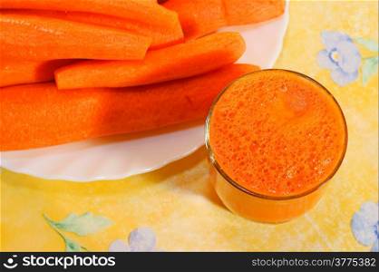 Carrot Juice in Glass. Yellow background.