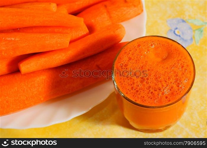 Carrot Juice in Glass. Yellow background.