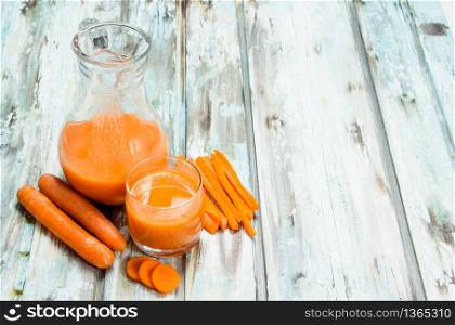 Carrot juice in the jug. On wooden background. Carrot juice in the jug.