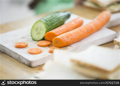 Carrots and cucumber on cutting board in kitchen