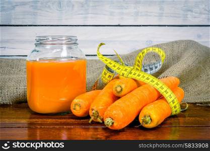 Carrots and juice on a wooden table with measure tape