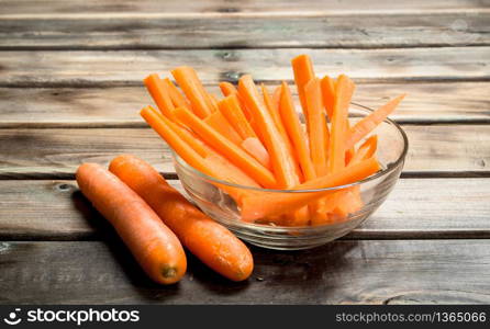 Carrots in a glass bowl. On wooden background. Carrots in a glass bowl.