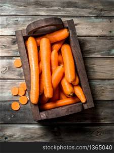 Carrots in a wooden box. On wooden background. Carrots in a wooden box.