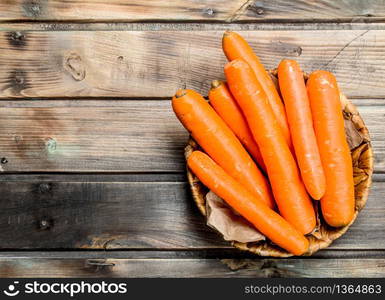 Carrots in the basket. On wooden background. Carrots in the basket.