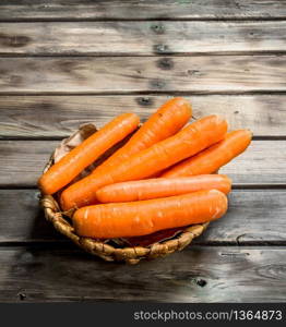 Carrots in the basket. On wooden background. Carrots in the basket.