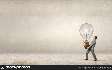 Carrying out an idea. Young businessman carrying big light bulb in hands
