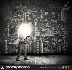 Carrying out an idea. Young businessman carrying light bulb on his back