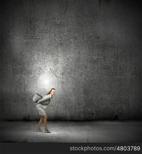 Carrying out an idea. Young businesswoman carrying light bulb on back