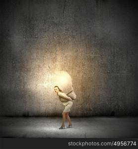 Carrying out an idea. Young businesswoman carrying light bulb on back