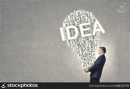 Carrying out idea. Young businessman carrying in hands bulb idea concept