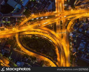 Cars driving on bridge roads shaped curve highways with skyscraper buildings. Aerial view of Expressway Bangna, Klong Toey in structure of architecture concept, Urban city, Bangkok at night, Thailand.