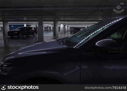 cars in spooky and dimly lit parking garage with strange lights