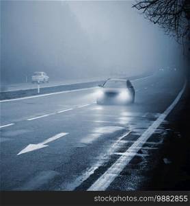 Cars in the fog. Bad winter weather and dangerous automobile traffic on the road. Light vehicles in foggy day.