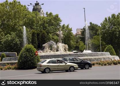 Cars moving on a road in front of a fountain, Fountain Of Neptune, Madrid, Spain