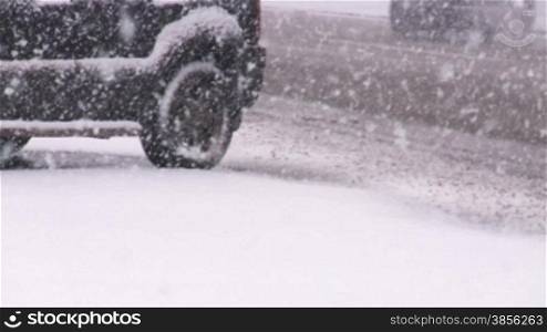 Cars on slippery road in blizzard.