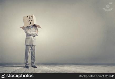 Carton head. Businessman wearing carton box with drawn emotions on head
