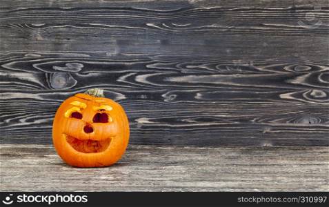 Carved for the celebration of the Halloween holiday pumpkin orange color, lie on a wooden black surface on a black wooden wall. Halloween holiday pumpkin