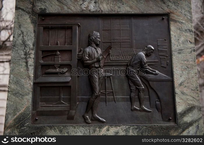 Carved plaques on the side of the Benjamin Franklin statue in Boston, Massachusetts, USA