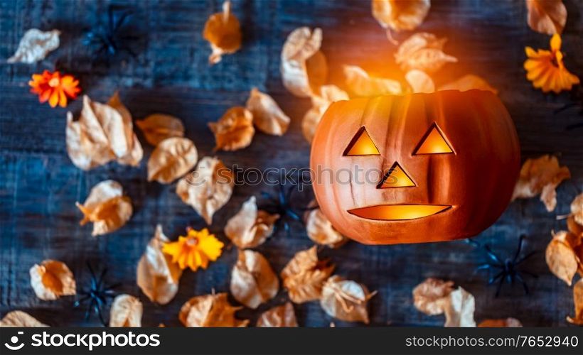 Carved Pumpkin as Jack-o-lantern with Grinning Face. Spooky Decoration for Halloween Party. Festive Still Life over Autumnal Leaves. Traditional American Holiday.