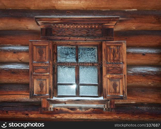 Carved window with shutters of old wooden house. Open air museum of Wooden Architecture and Folk Art in Malye Korely, near Arkhangelsk, Russia. Winter time.