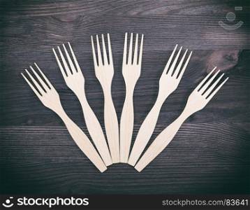 carved wooden forks on a brown background, close up