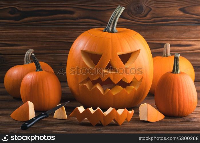Carving Halloween pumpkin. Carving of Halloween pumpkin in progress, pieces and cutting knife on wooden background