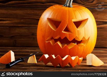 Carving of Halloween pumpkin in progress, knife on wooden background. Carving of Halloween pumpkin