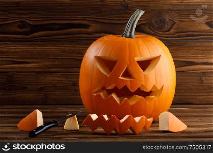 Carving of Halloween pumpkin in progress, pieces and cutting knife on wooden background. Carving Halloween pumpkin
