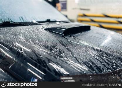 Carwash service, car covered with foam, front view. Auto detailing, high pressure washing on special station. Carwash service, car covered with foam