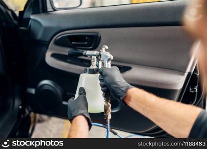 Carwash service, male worker in gloves using special spray. Professional dry cleaning of car door trim, vehicle interior hygiene. Carwash service, male worker in gloves using spray