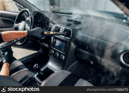 Carwash service, worker in gloves cleans salon with steam cleaner. Professional dry cleaning of car interior. Carwash, worker cleans salon with steam cleaner
