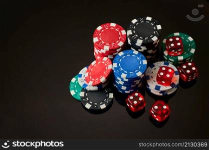 Casino chips and dices on dark reflective background with copy space.. Casino chips and dices on dark reflective background with copy space