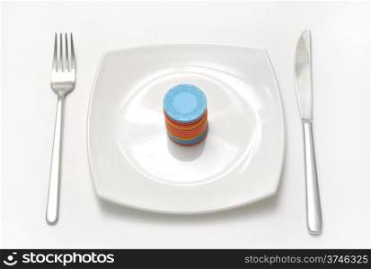 casino chips on white plate with fork and knife