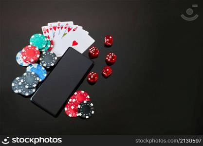 Casino chips, playing cards, dices and mobile phone on dark reflective background.. Casino chips, playing cards, dices and mobile phone on dark reflective background